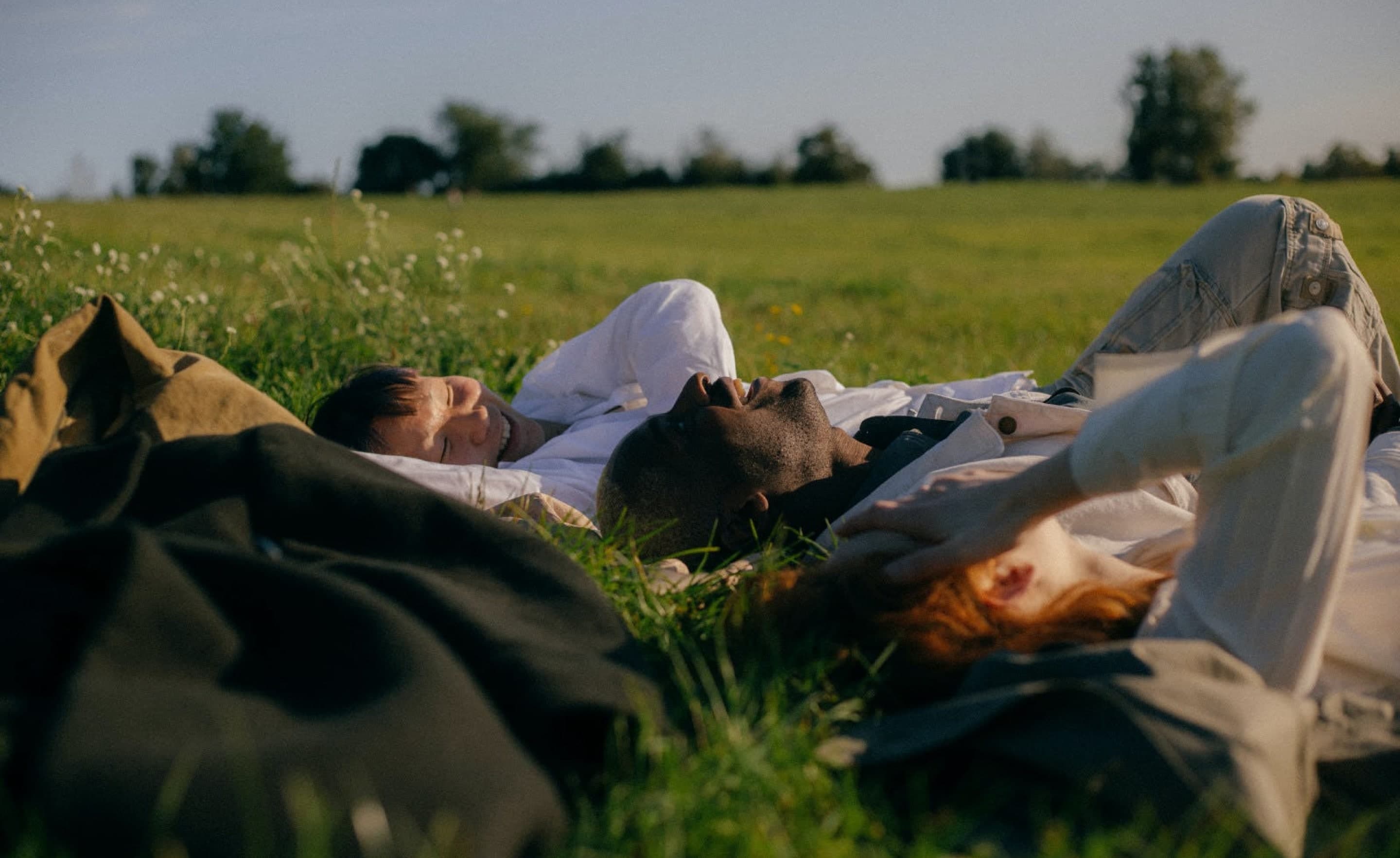 Joyroots, people laying down happily in the grass on a sunny day.